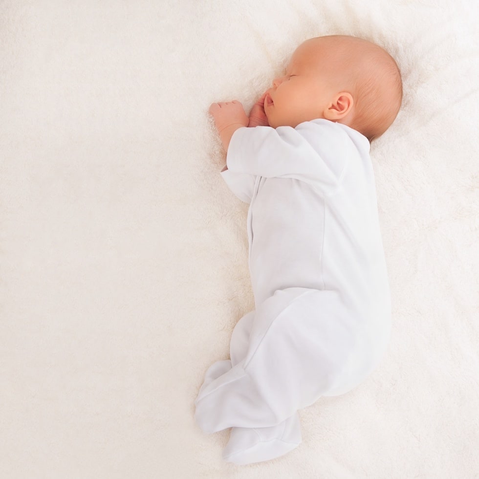 Newborn sleeping in white romper